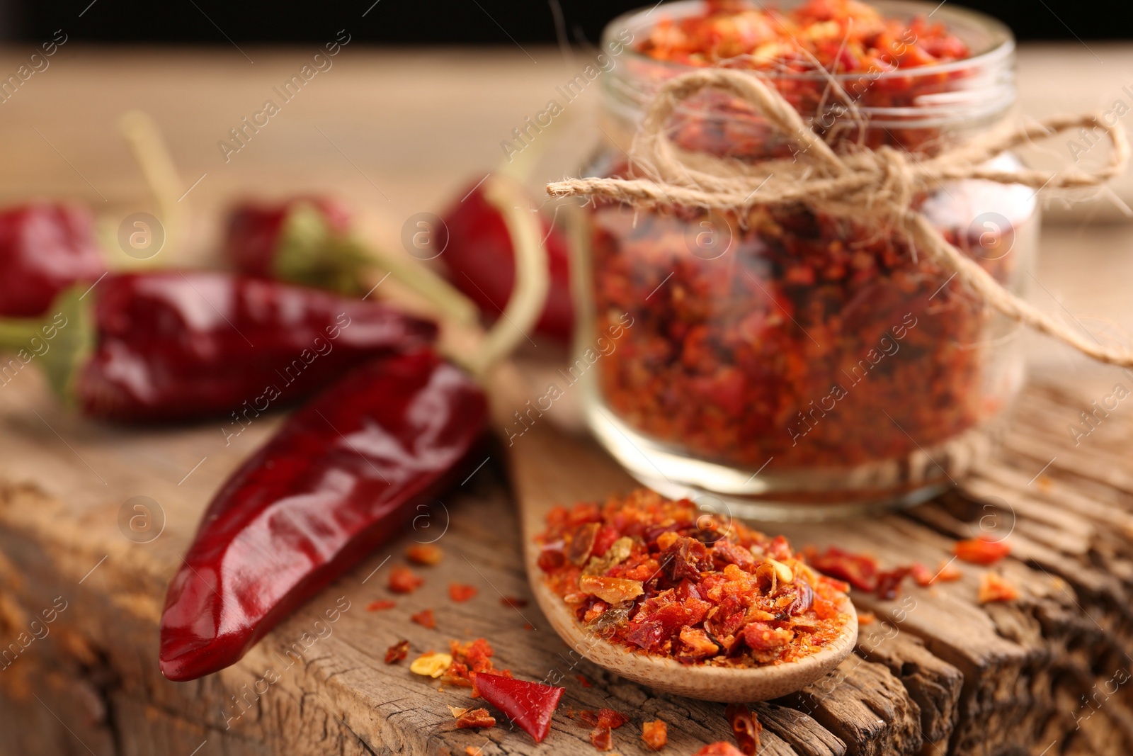 Photo of Chili pepper flakes and pods on wooden table, closeup. Space for text