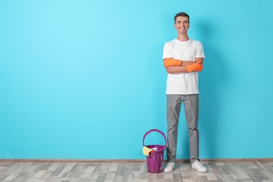 Man with cleaning supplies near color wall