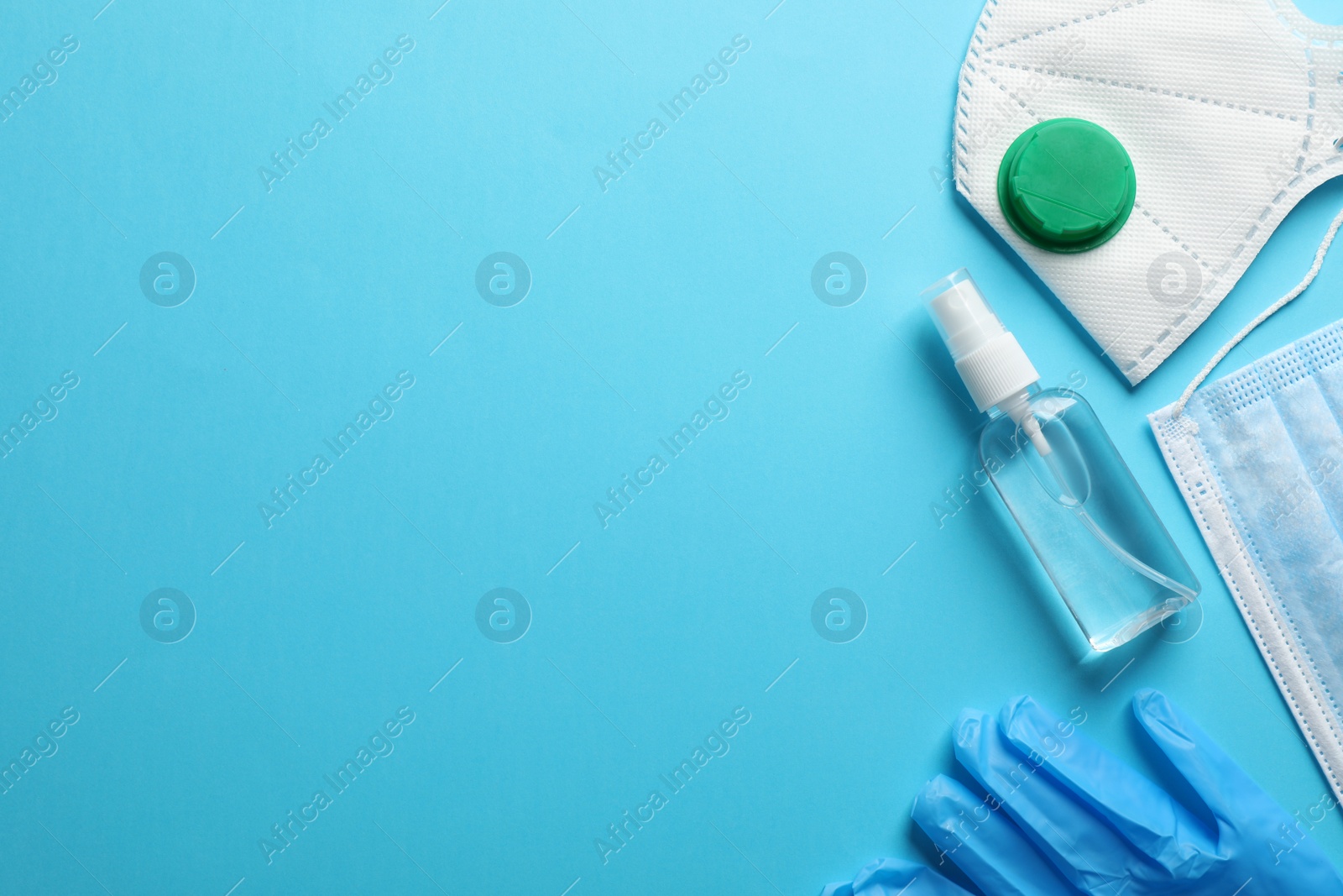 Photo of Medical gloves, masks and hand sanitizer on light blue background, flat lay with space for text. Safety equipment