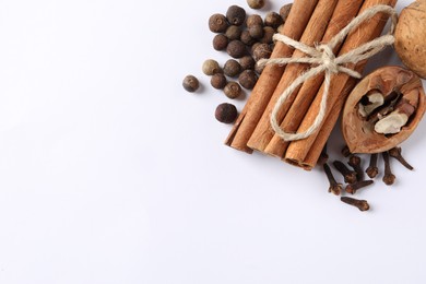 Different spices and nuts on white table, flat lay. Space for text