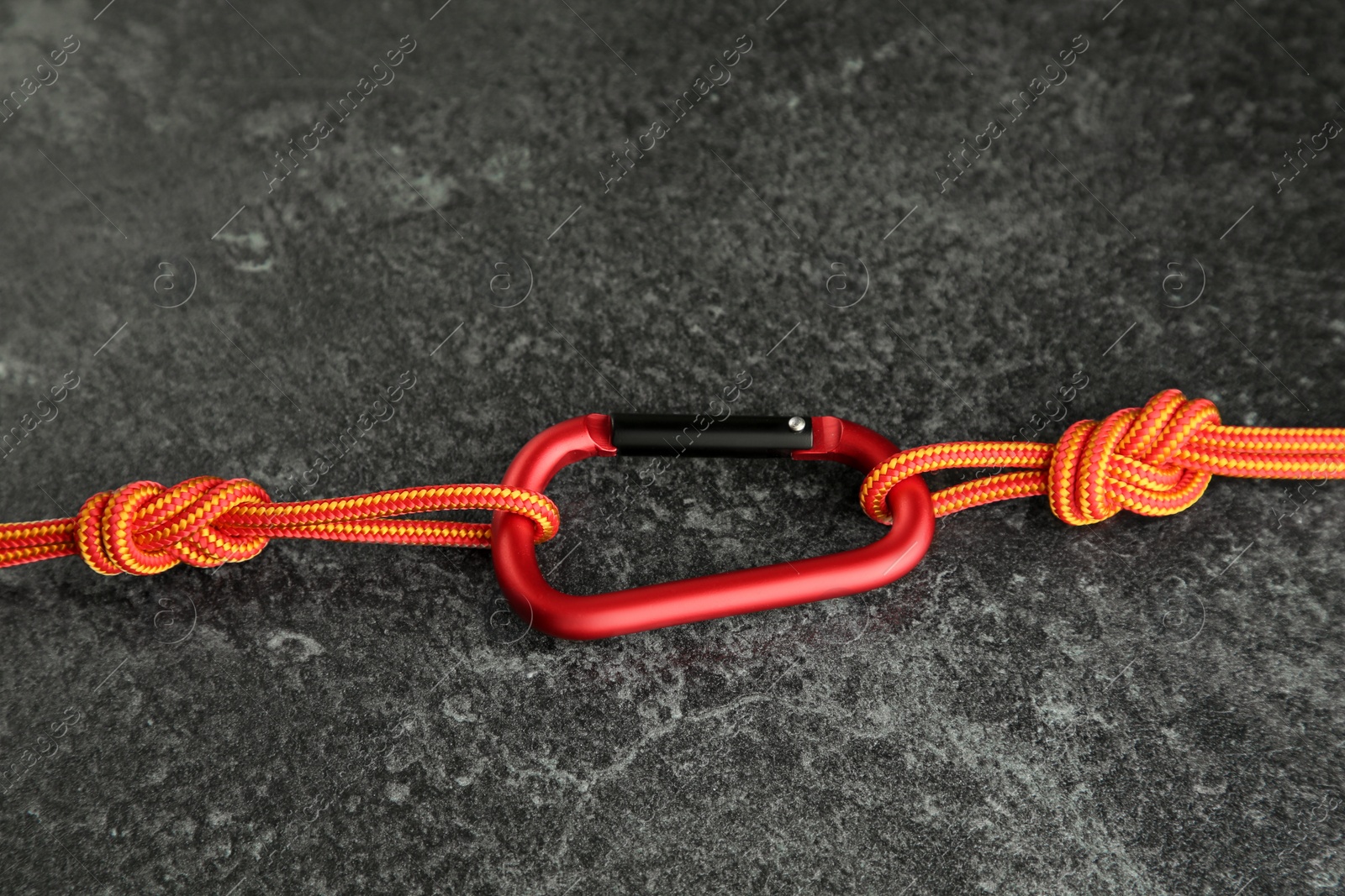 Photo of One metal carabiner with ropes on black table