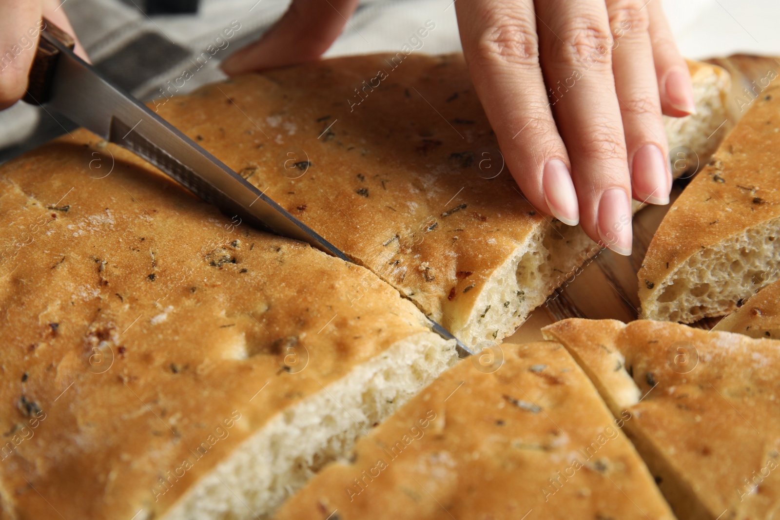 Photo of Woman cutting bread on wooden board, closeup