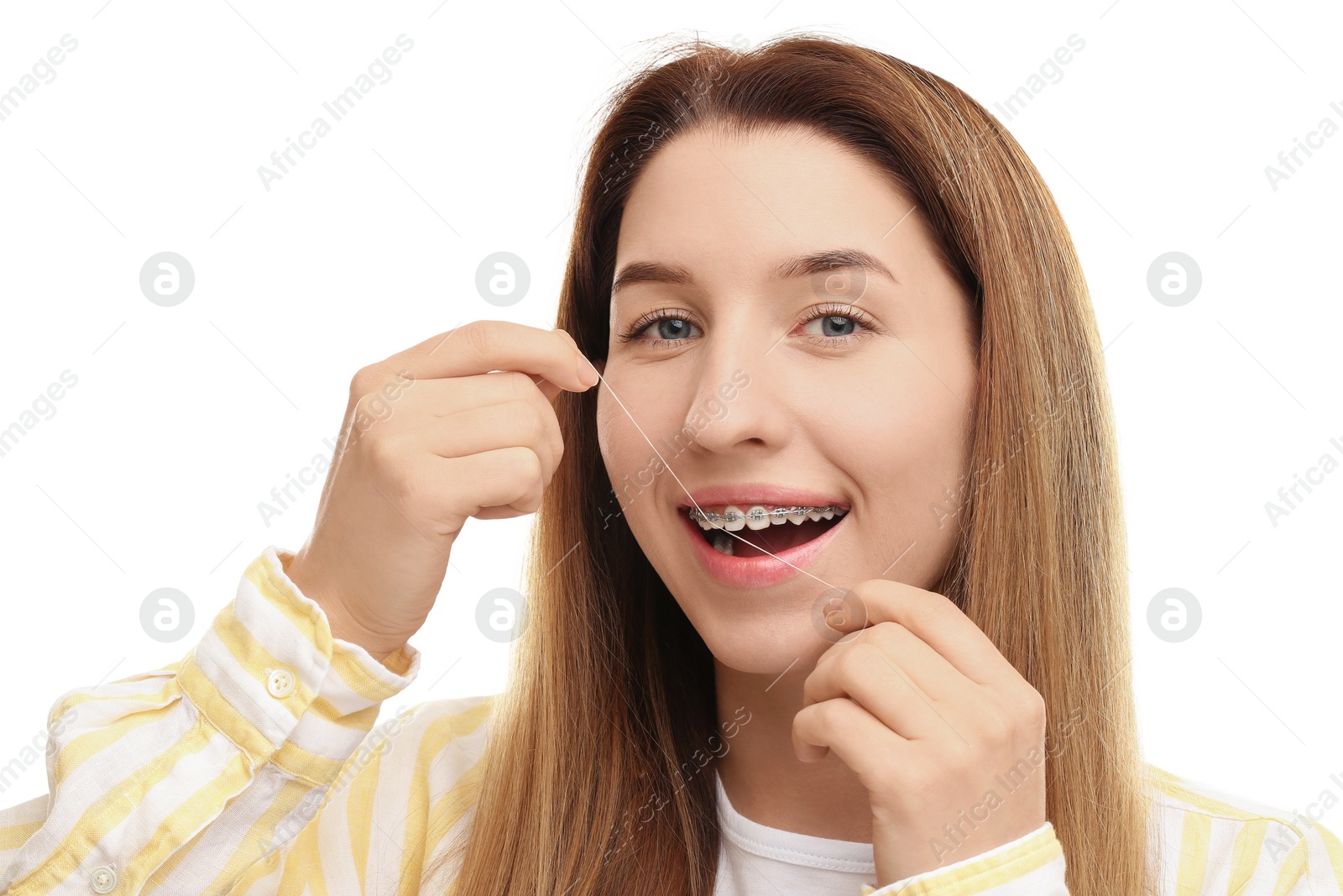 Photo of Smiling woman with braces cleaning teeth using dental floss on white background