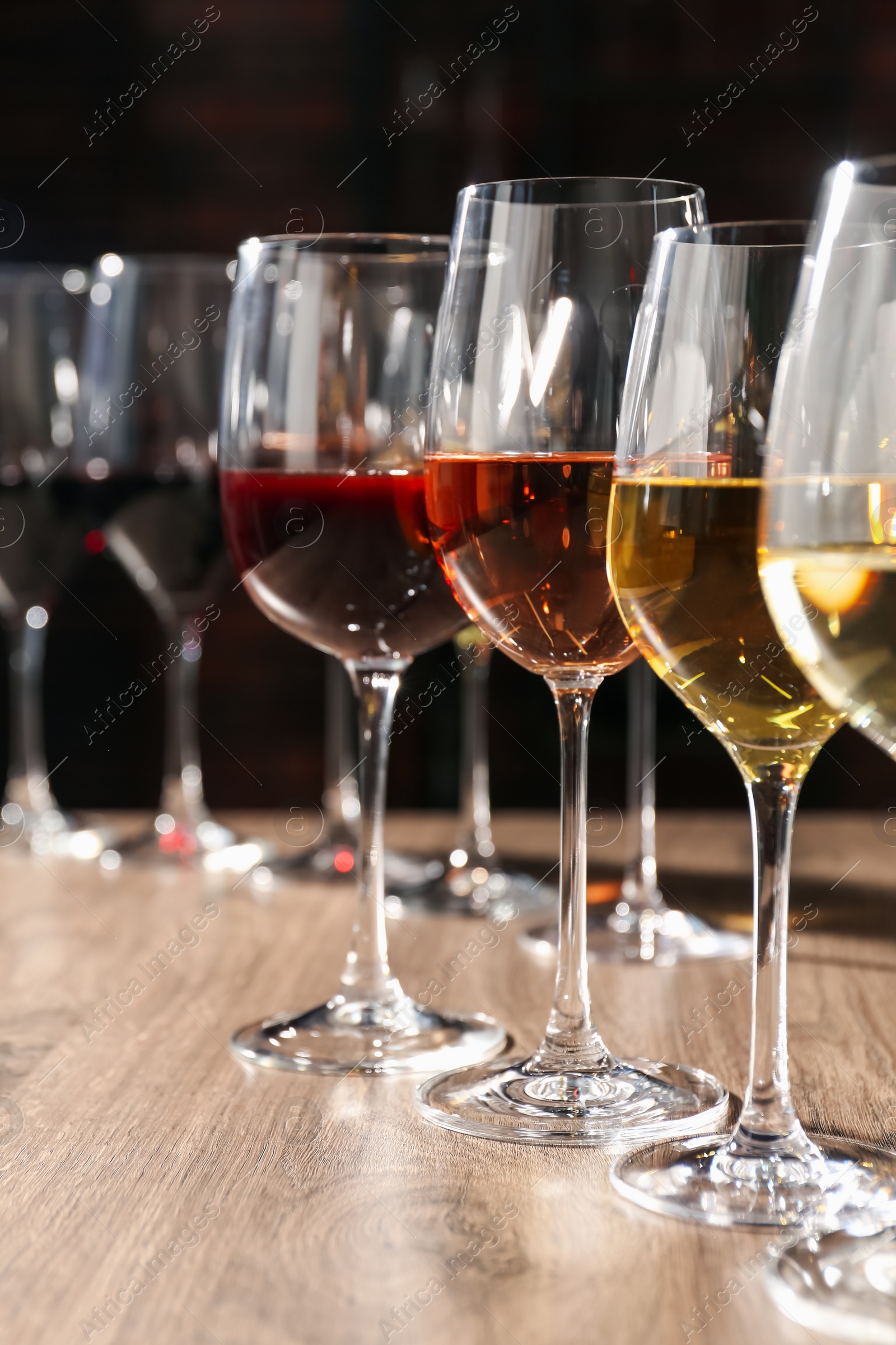 Photo of Different tasty wines in glasses on wooden table