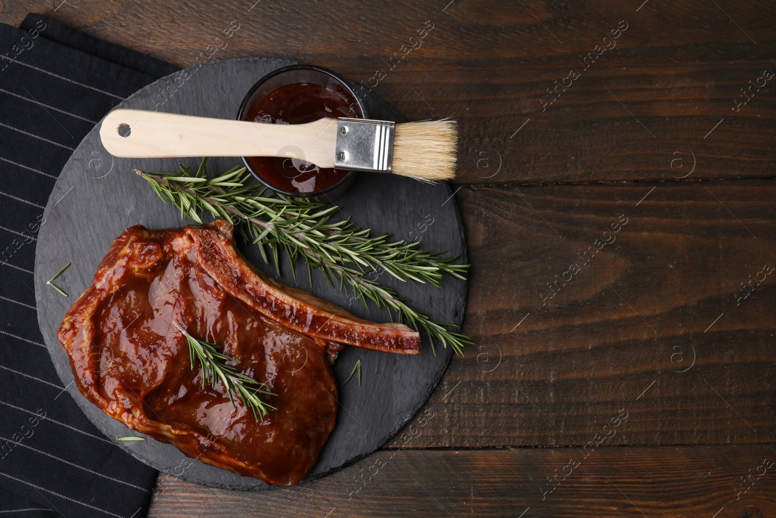 Photo of Tasty meat, rosemary, marinade and basting brush on wooden table, top view. Space for text