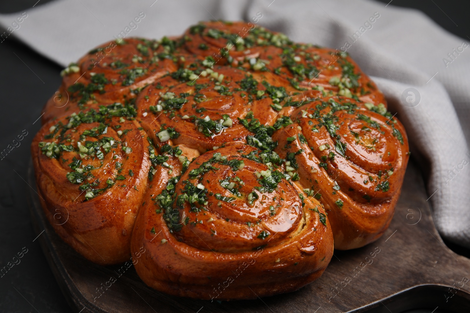 Photo of Traditional Ukrainian garlic bread with herbs (Pampushky) on black table, closeup