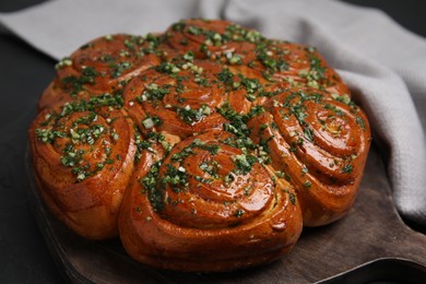 Traditional Ukrainian garlic bread with herbs (Pampushky) on black table, closeup