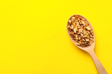 Photo of Spoon with dried orange zest seasoning on yellow background, top view. Space for text