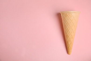 Photo of Empty wafer ice cream cone on pink background, top view. Space for text