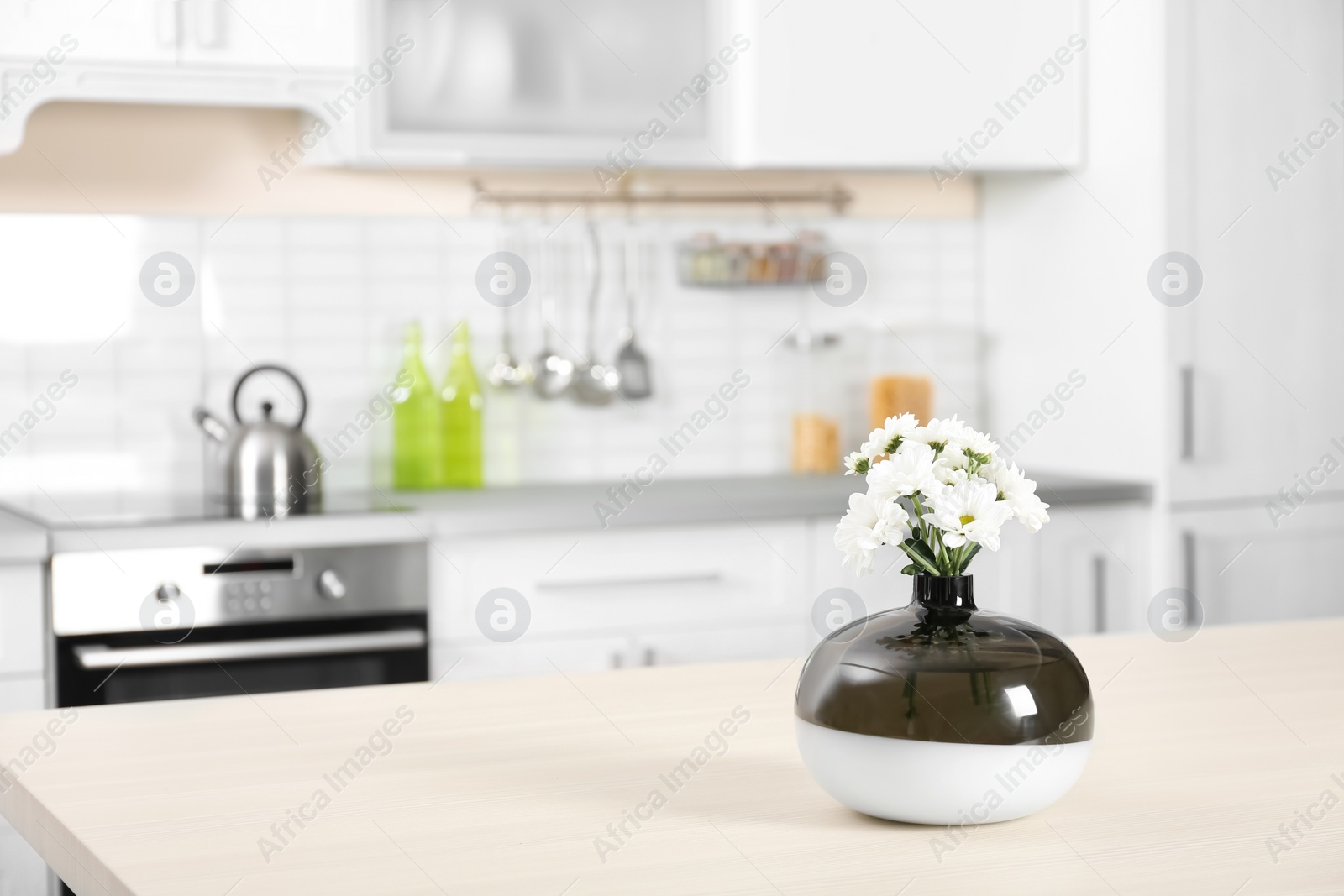 Photo of Vase with beautiful flowers on table in kitchen interior. Space for text