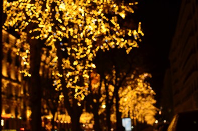 Photo of Blurred view of street with beautiful lights on trees at night. Bokeh effect