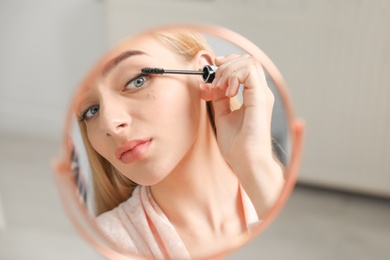 Young woman with eyelash loss problem applying mascara indoors