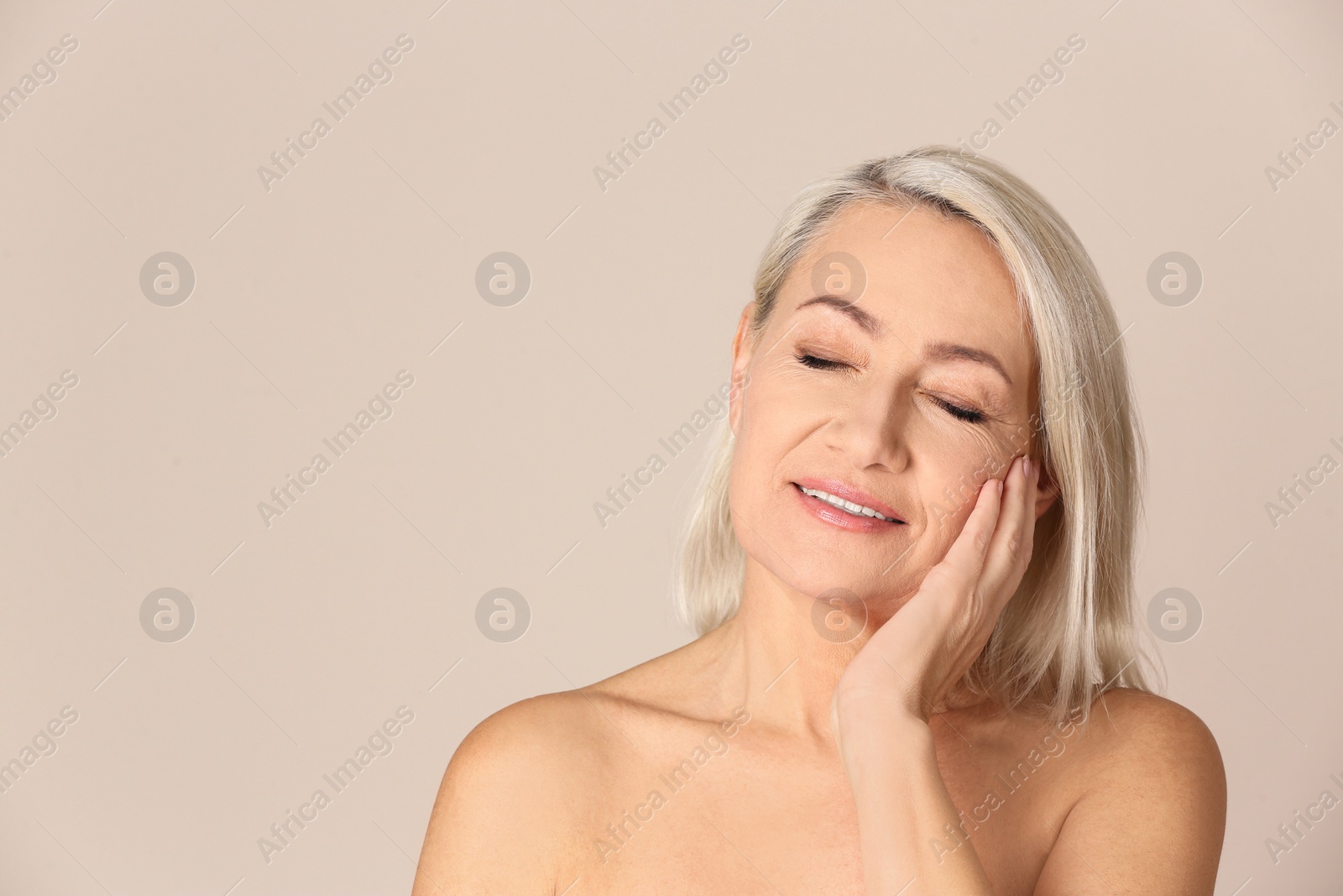 Photo of Portrait of beautiful mature woman on beige background. Space for text