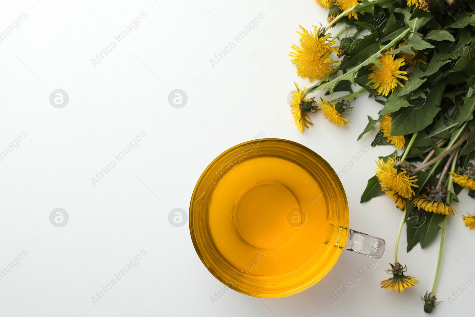 Photo of Delicious fresh tea and beautiful dandelion flowers on white background, flat lay. Space for text
