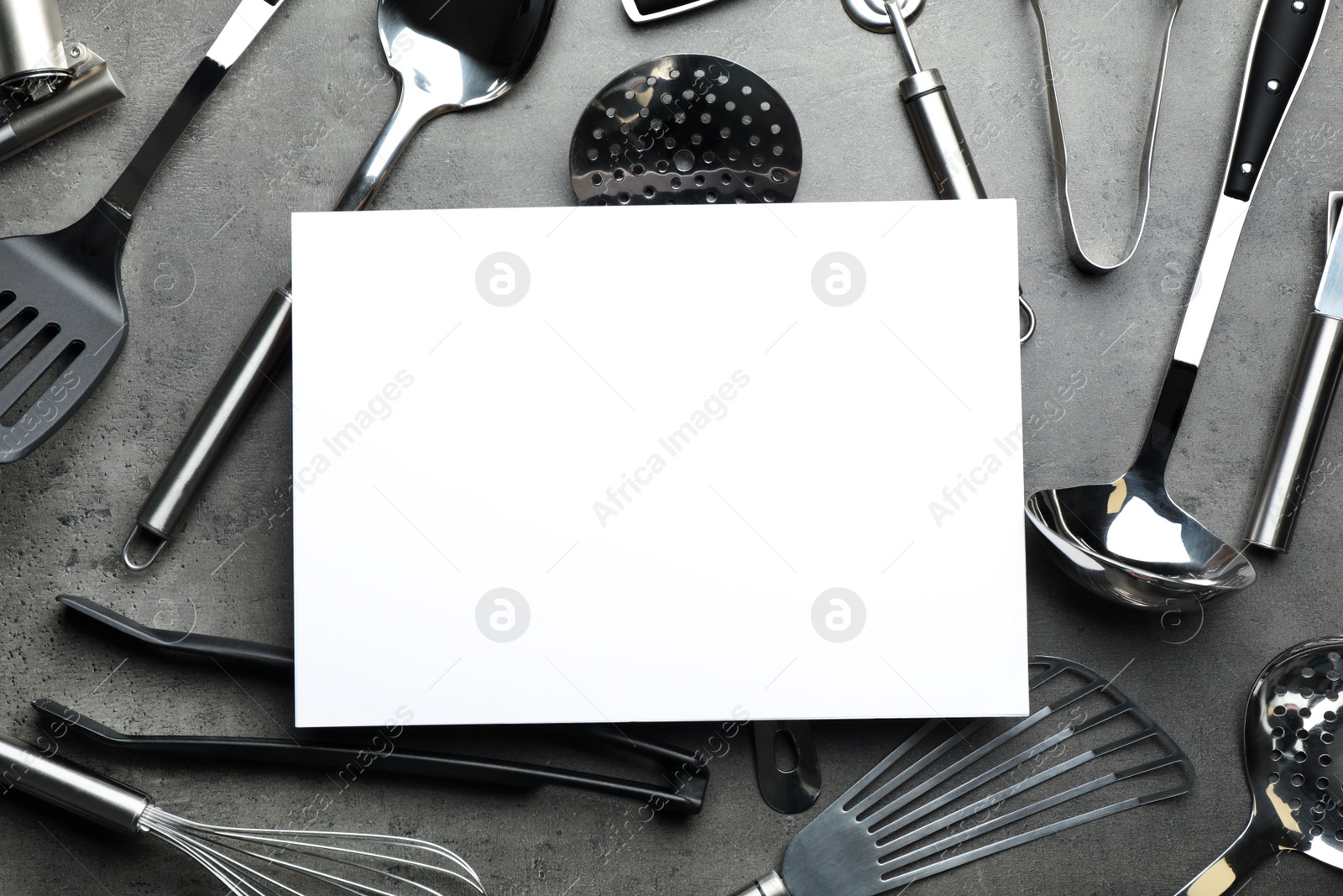 Photo of Flat lay composition with different kitchen utensils and empty card on grey background, space for text