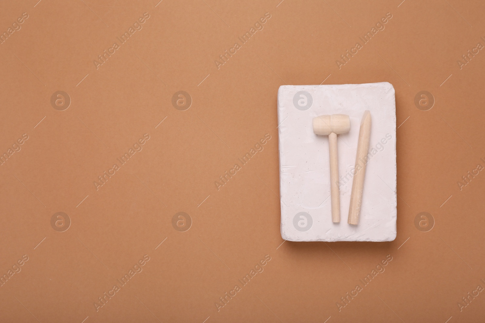 Photo of Educational toy for motor skills development. Excavation kit (plaster and digging tools) on brown background, top view with space for text