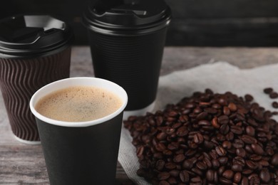 Photo of Coffee to go. Paper cups with tasty drink and roasted beans on table, closeup. Space for text