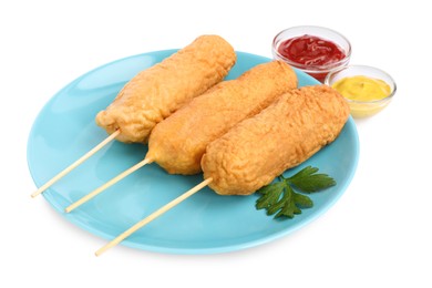 Photo of Delicious deep fried corn dogs with parsley and sauces on white background