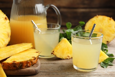 Photo of Delicious pineapple juice and fresh fruit on wooden table