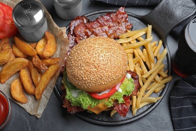 Photo of Fresh bacon burger and fries on grey table, above view