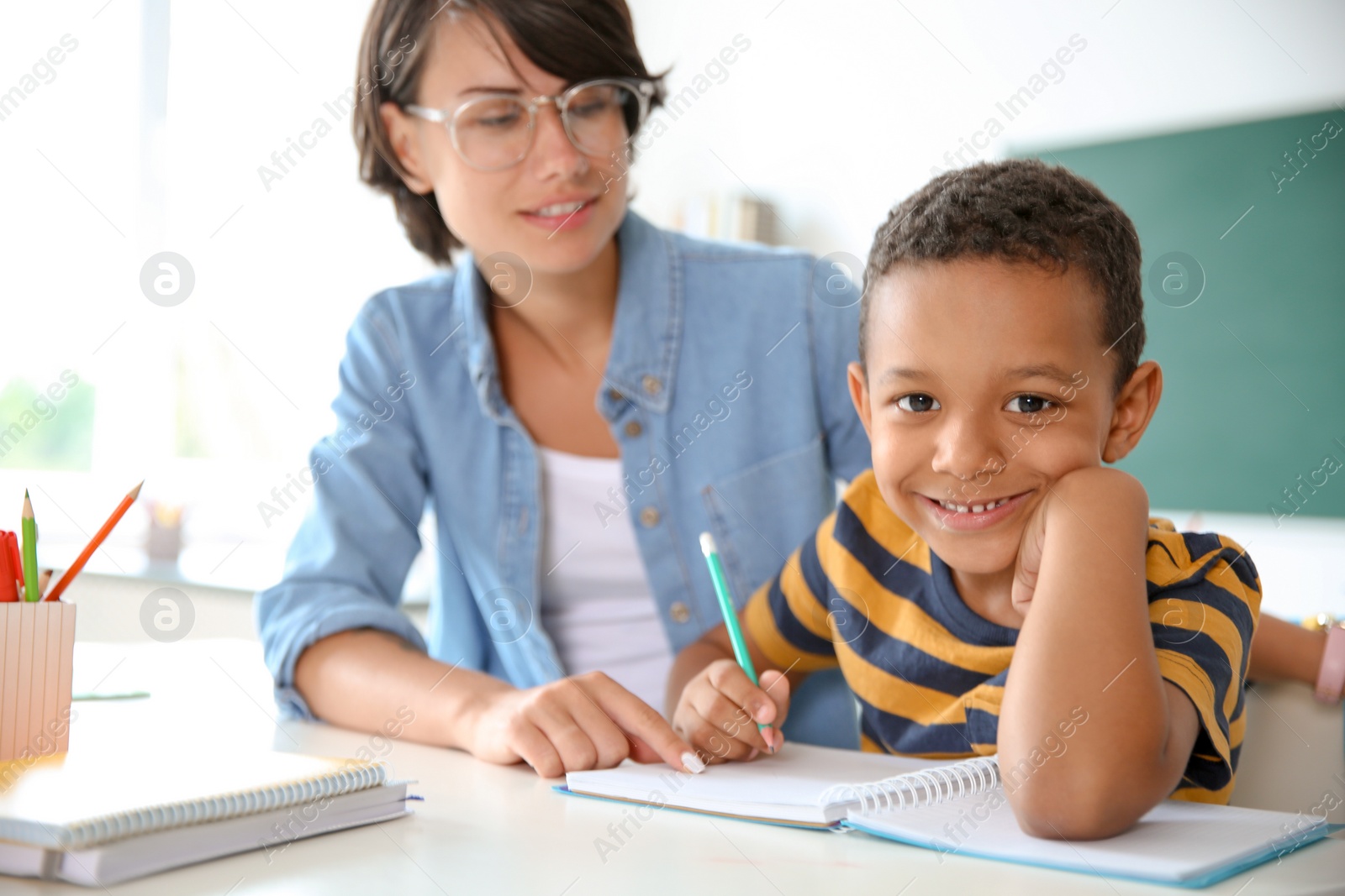 Photo of Female teacher helping child with assignment at school