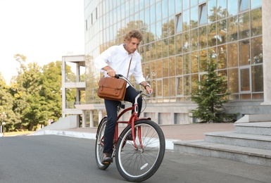 Photo of Attractive man riding bike on city street