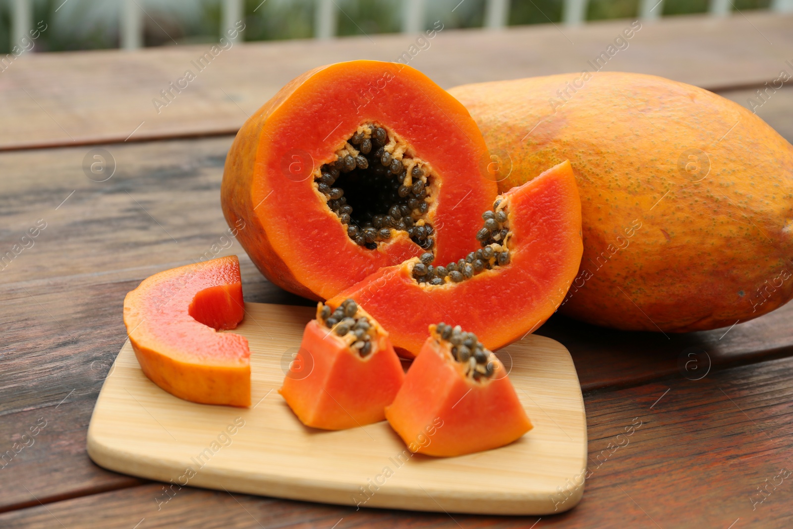 Photo of Ripe cut and whole papaya fruits on wooden table