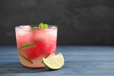 Photo of Glass of refreshing watermelon drink on blue wooden table against dark background. Space for text