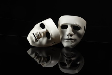 Plastic face masks on black mirror surface. Theatrical performance