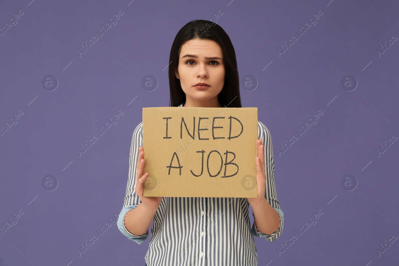 Photo of Unemployment problem. Unhappy woman holding sign with phrase I Need A Job on violet background