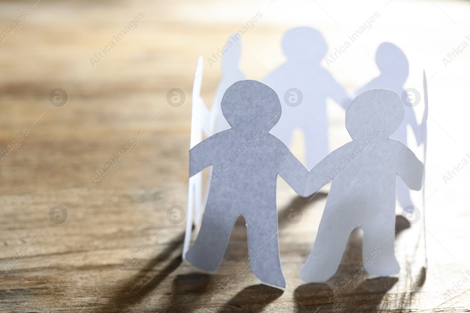 Photo of Paper people chain making circle on wooden background, space for text. Unity concept