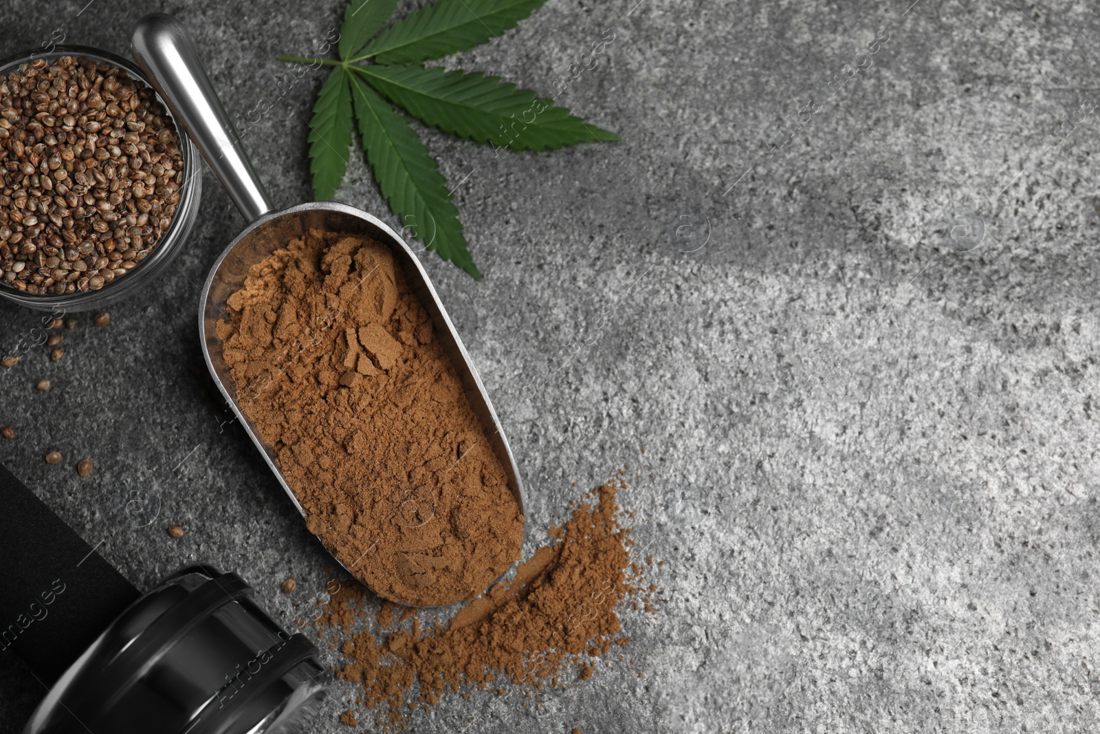 Photo of Hemp protein powder, fresh leaf, seeds and dumbbell on grey table, flat lay. Space for text