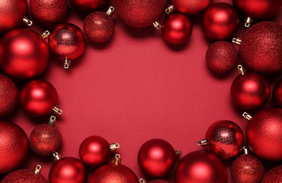 Frame of beautiful Christmas balls on red background, top view. Space for text