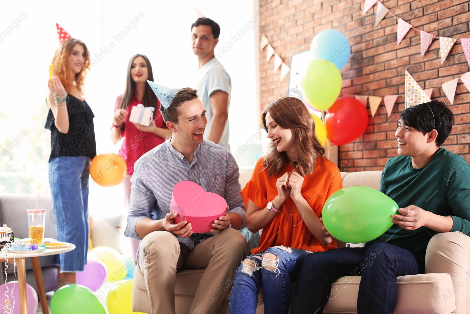 Photo of Young people having birthday party in decorated room