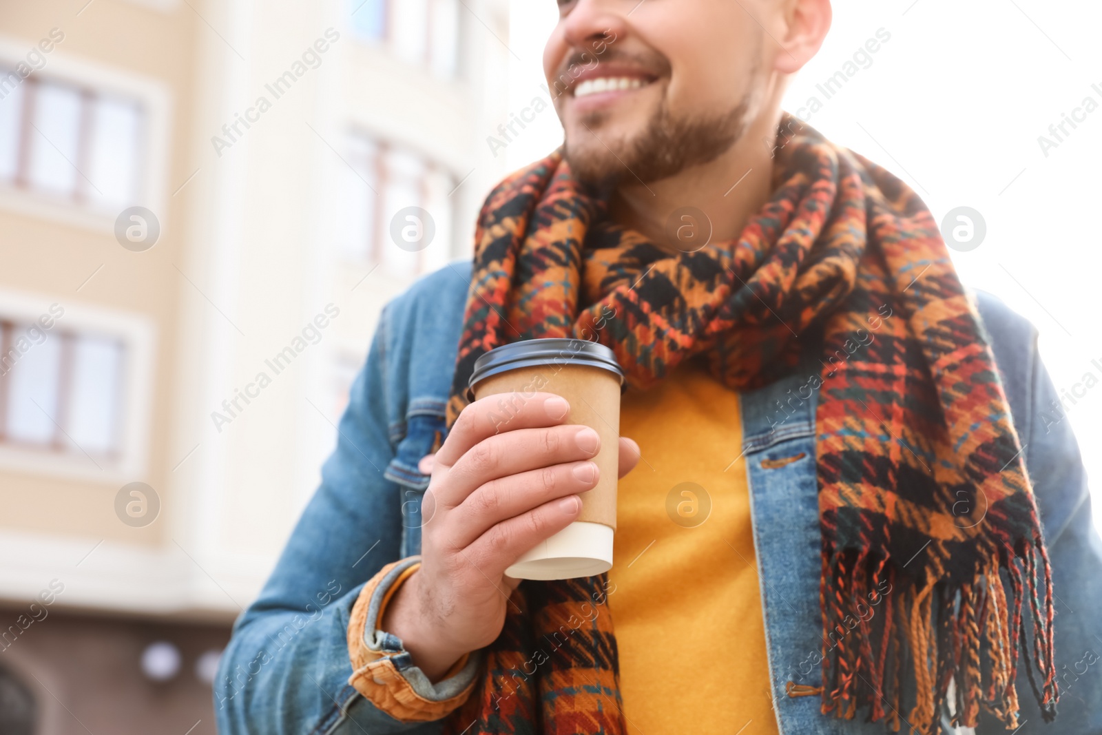 Photo of Man with cup of coffee on city street in morning, closeup