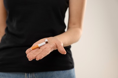 Photo of Stop smoking concept. Woman holding broken cigarette on beige background, closeup. Space for text