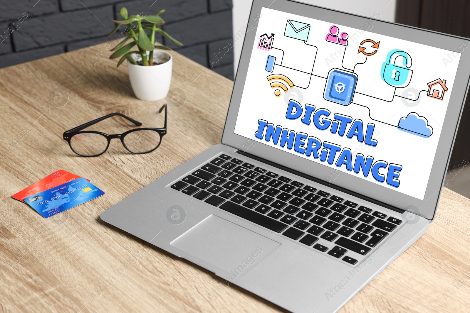 Image of Laptop with text Digital Inheritance and scheme with many different icons on screen. Workplace with device and plastic cards on wooden table