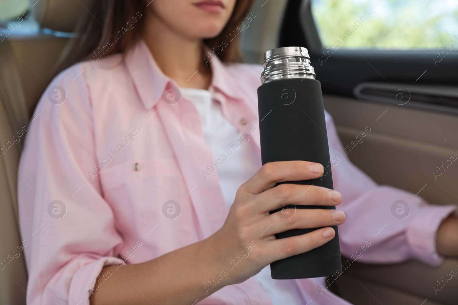 Photo of Woman with thermos inside of car, closeup