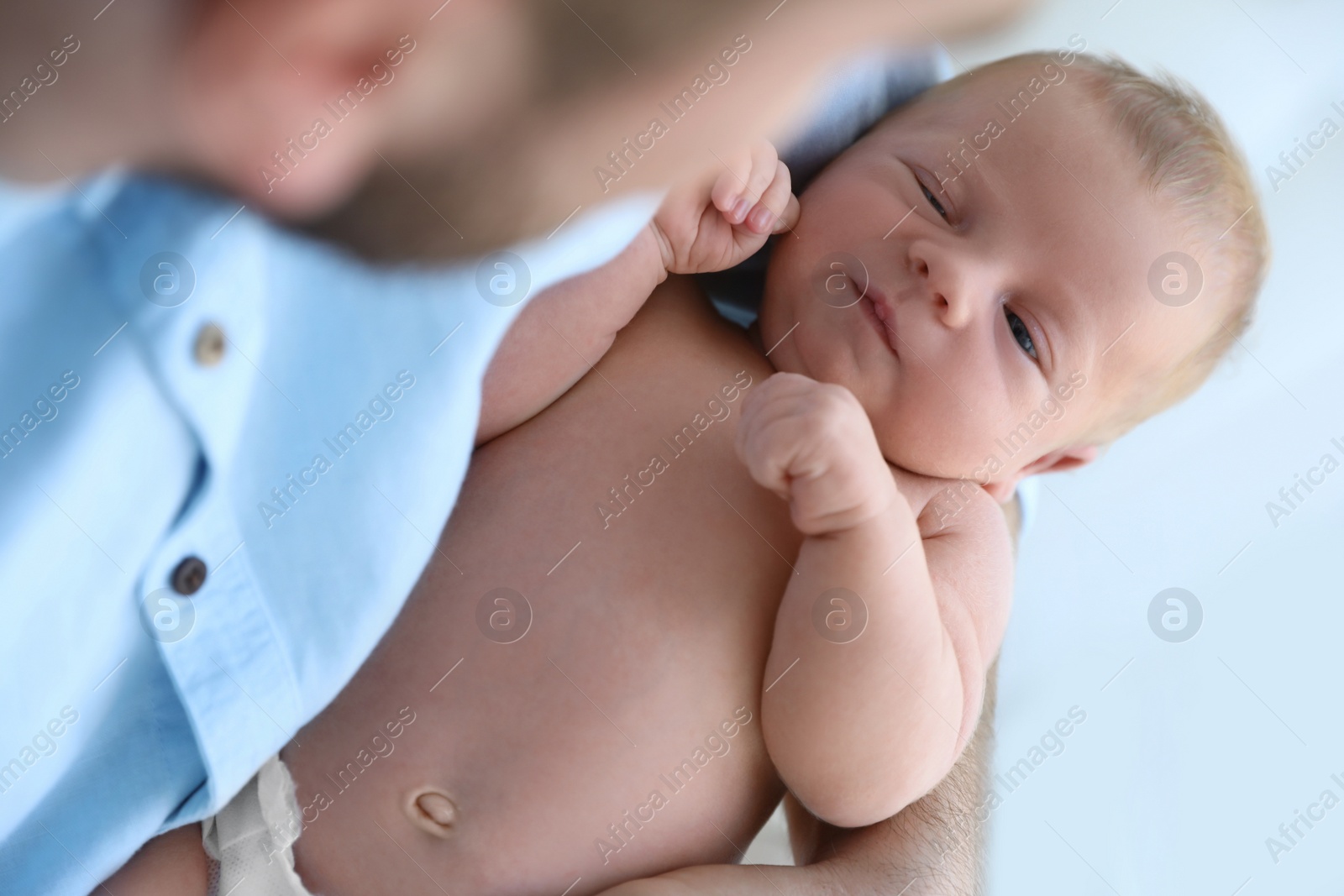 Photo of Father holding his cute newborn baby at home, closeup