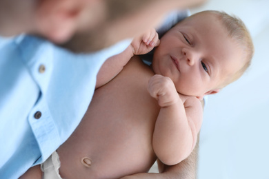 Photo of Father holding his cute newborn baby at home, closeup