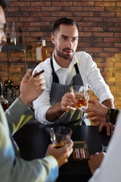 Photo of Bartender giving glass of whiskey to client in bar