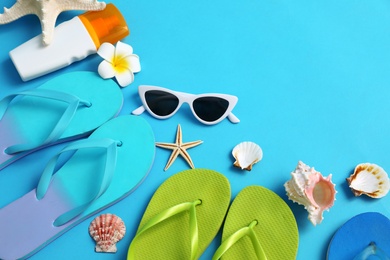 Photo of Flat lay composition with different flip flops on blue background, space for text. Summer beach accessories