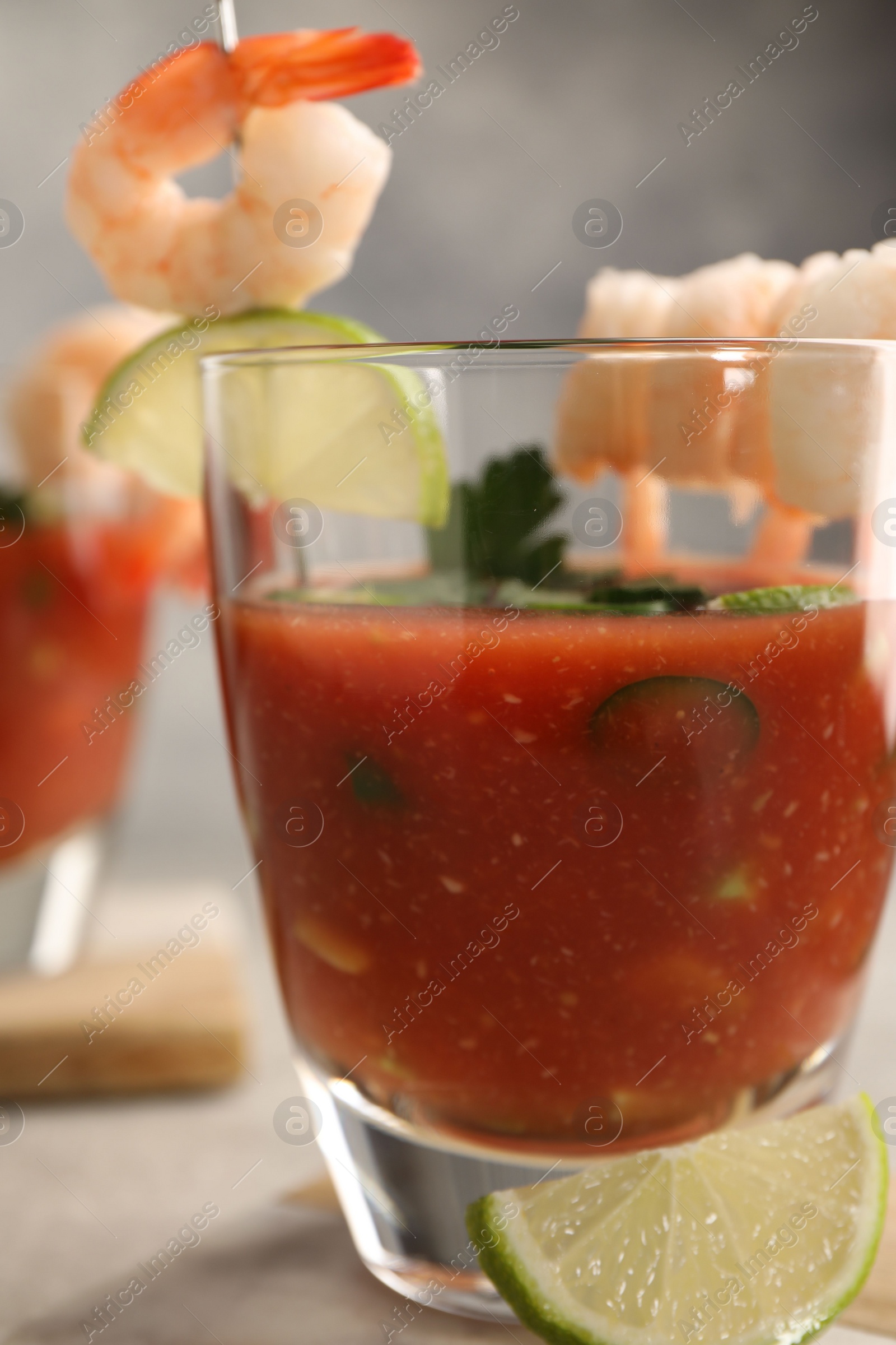 Photo of Tasty shrimp cocktail with sauce in glass and lime on table, closeup