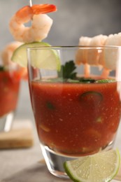 Tasty shrimp cocktail with sauce in glass and lime on table, closeup