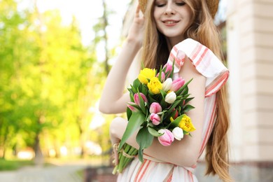 Photo of Beautiful teenage girl with bouquet of tulips outdoors, focus on flowers. Space for text