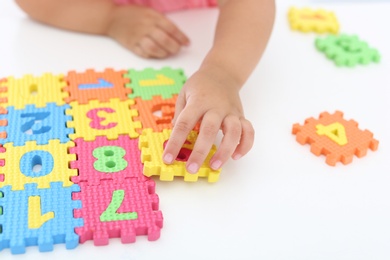 Little girl playing with colorful puzzles at white table, closeup. Educational toy