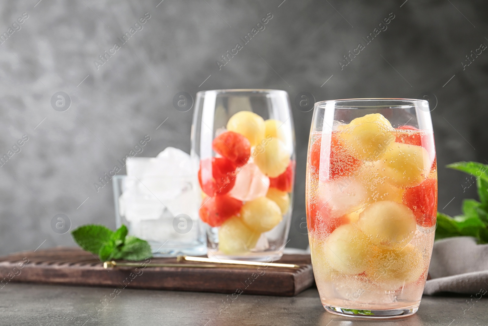 Photo of Glass of melon and watermelon ball cocktail on grey table. Space for text