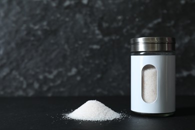 Photo of Stylish shaker with salt on black table, space for text