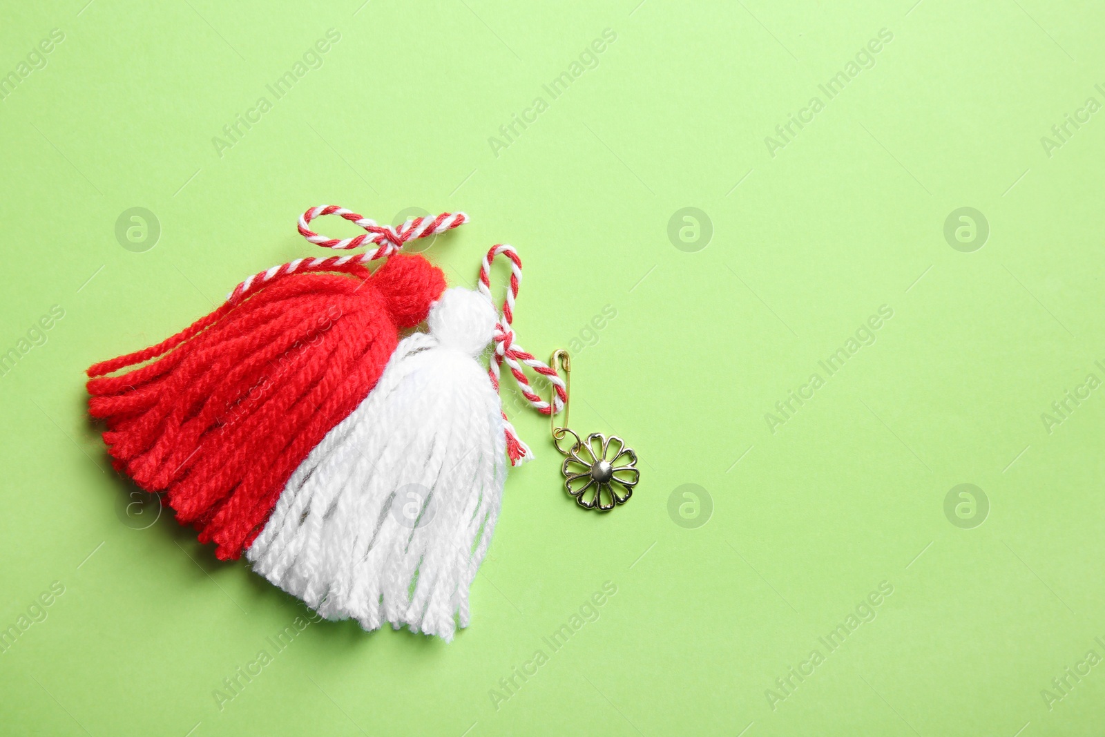 Photo of Traditional martisor on green background, top view with space for text. Beginning of spring celebration