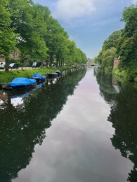 Beautiful view of city canal with moored boats surrounded by greenery